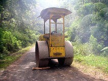 photo d’un compacteur sur une route traversant la forêt primaire de Bornéo