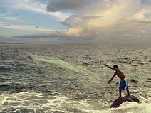 photo d’un pêcheur qui son jette filet à partir d’un rocher